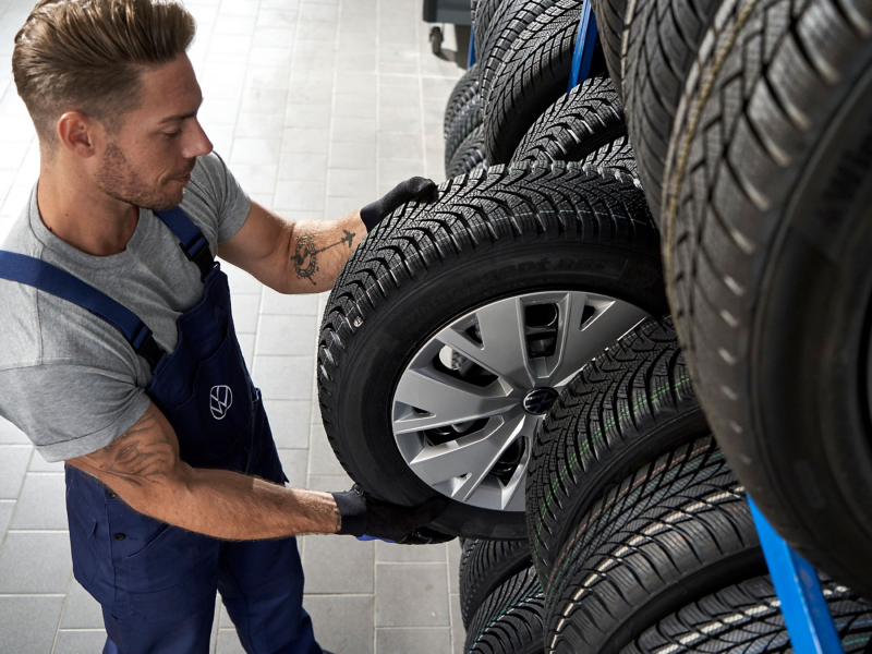 VW Servicemitarbeiter nimmt Rad mit VW Felge aus einem Regal – Rädereinlagerungs Service