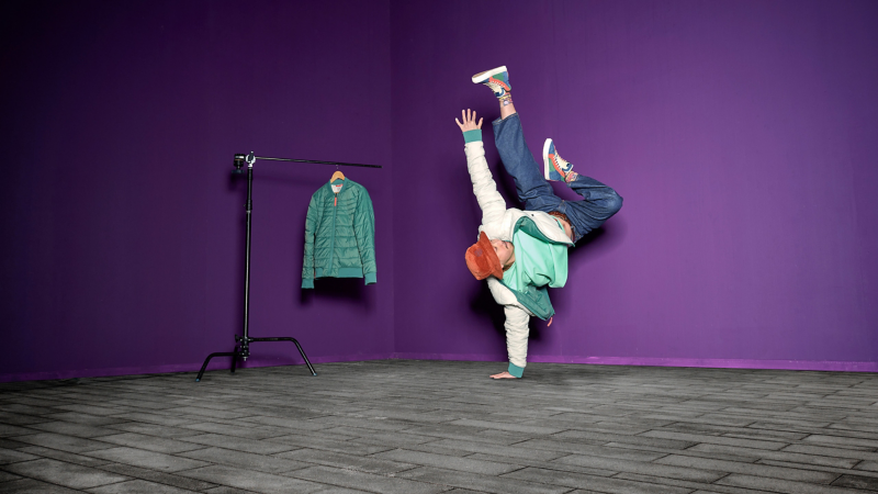 Mann mit Wendejacke aus der ID. Buzz Kollektion macht einarmigen Handstand – VW Fanartikel aus dem VW Zubehör Shop