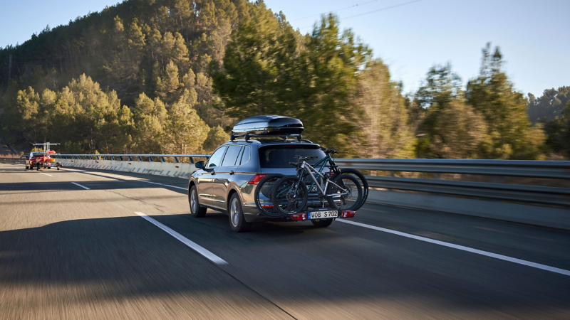 VW Tiguan Allspace mit VW Zubehör Dachbox und Fahrradträger aus VW Zubehör Shop fährt hinter VW ID.5 GTX mit Kajakanhänger